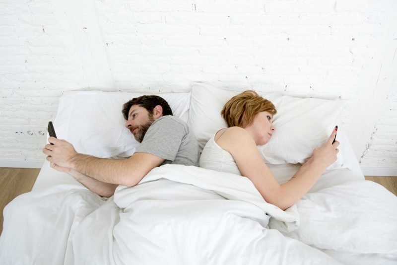 casal mexendo no celular na cama