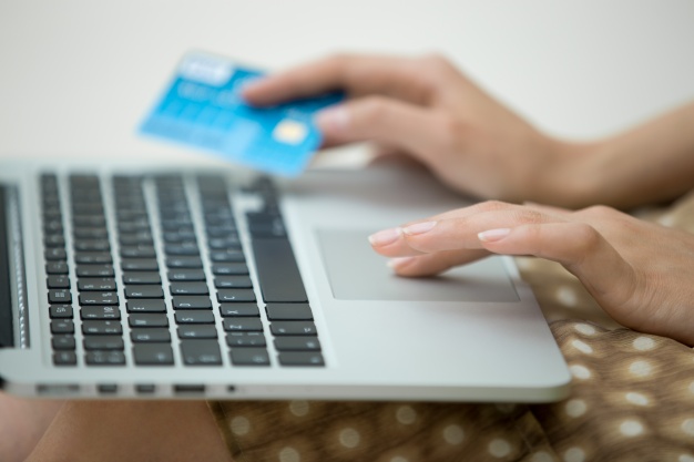mulher com notebook no colo e cartão de crédito nas mãos compras pela internet